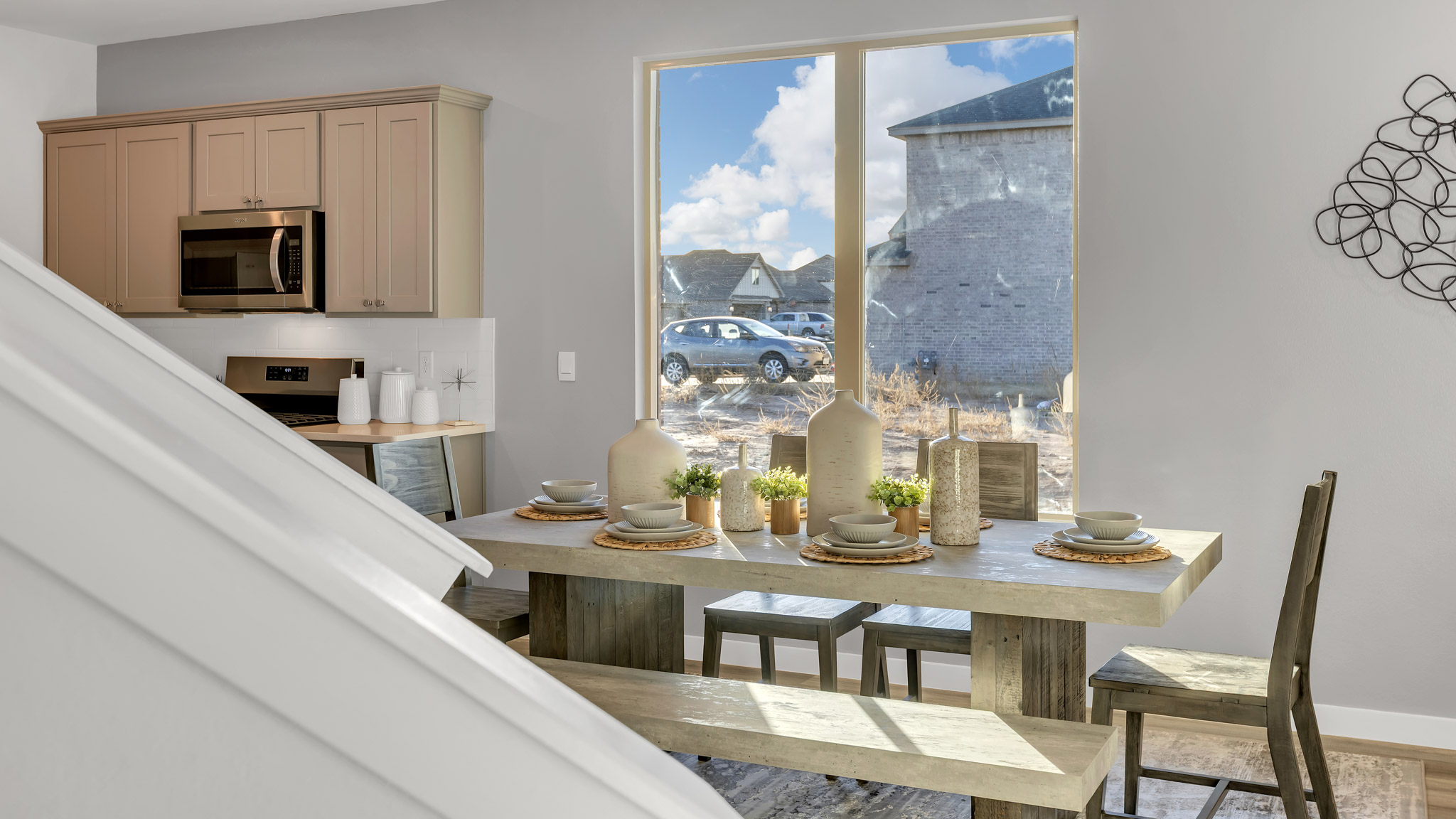 Carpeted staircase with wood tone handrails next to dinning area