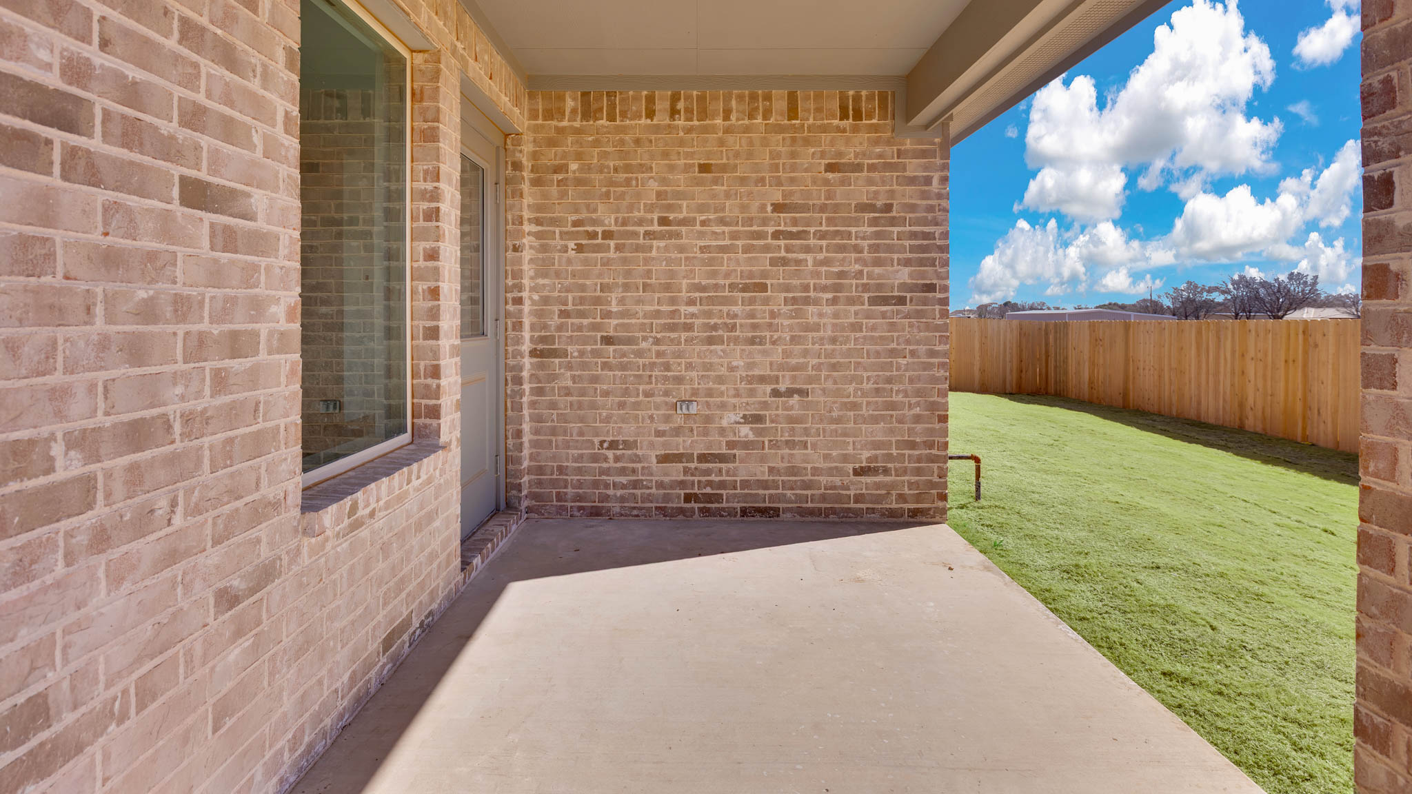 Covered back patio area overlooking spacious backyard
