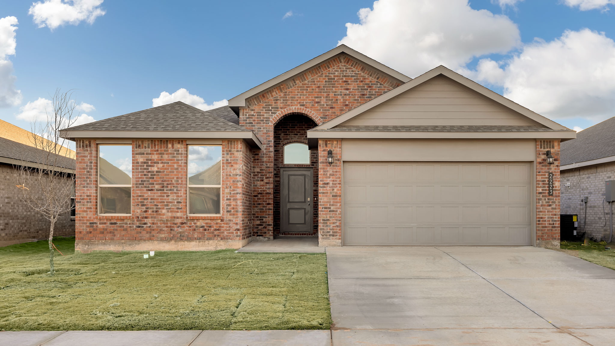 Single- story home with brick, stone, covered patio and two car garage