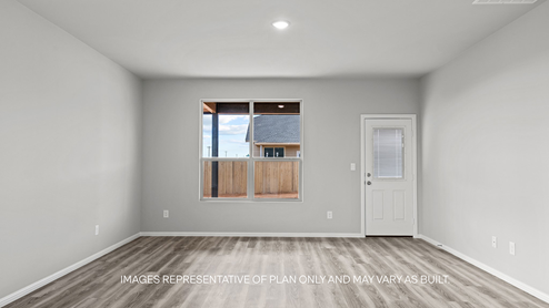 Open airy living room with vinyl plank flooring and windows overlooking the backyard
