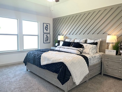 Primary bedroom with plush carpet and windows overlooking backyard