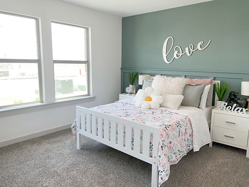Guest bedroom with plush carpet and windows overlooking front of home