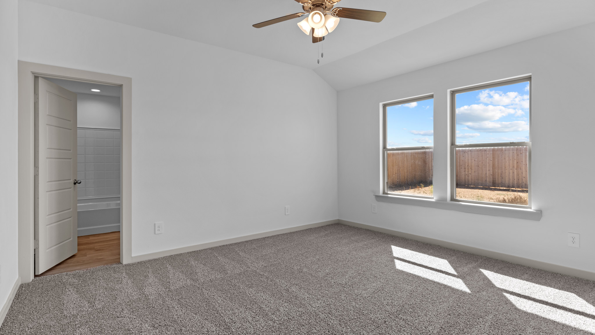 Primary bedroom with plush carpet and two windows