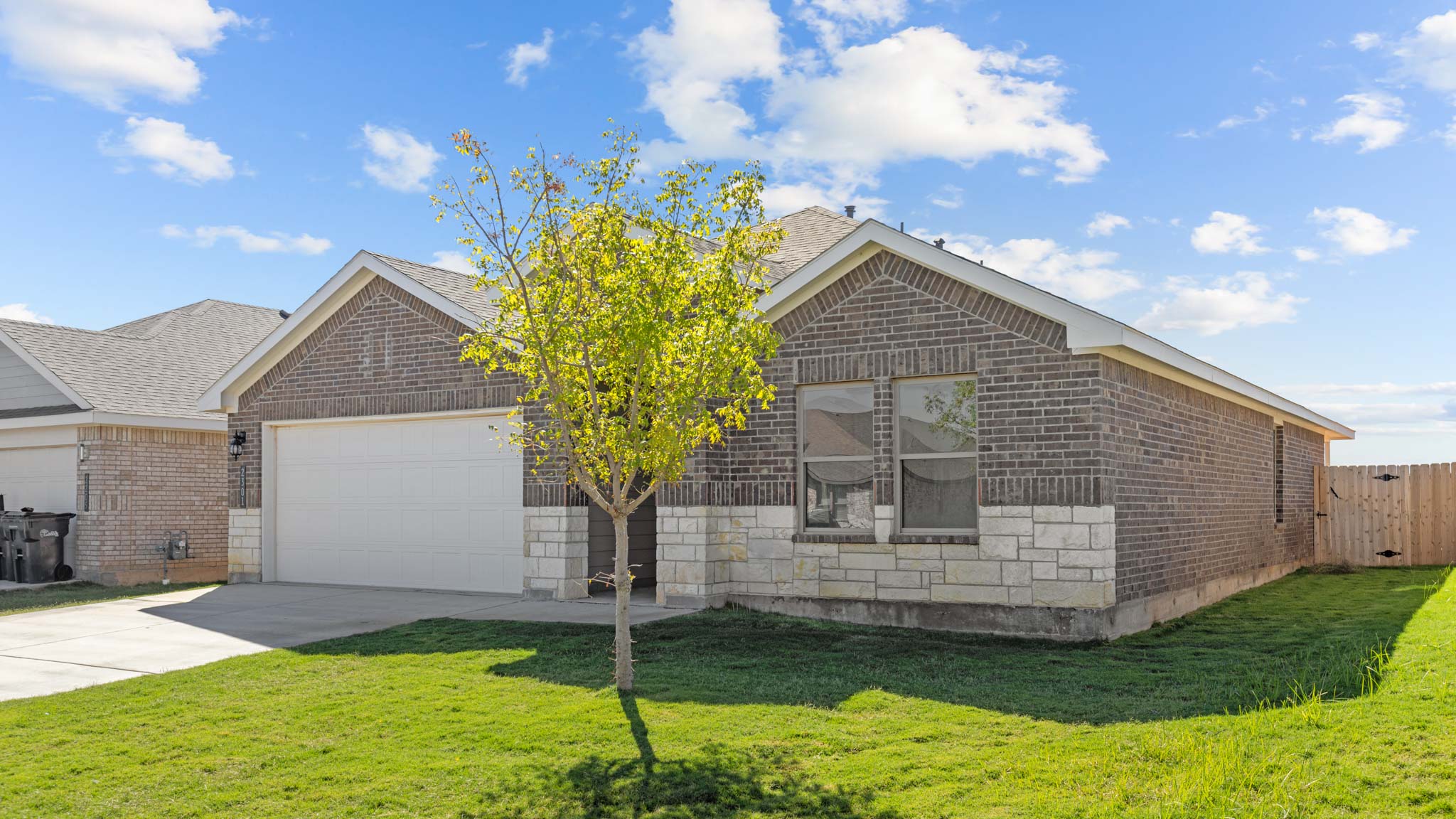 Single story home with brick, stone, covered patio with 2 car garage