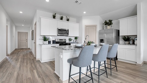 Kitchen peninsula with white cabinets and stainless steel appliances