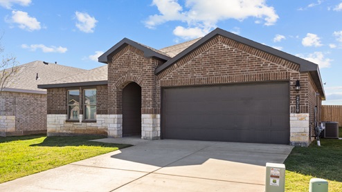 Single story home with brick, stone, covered patio with 2 car garage