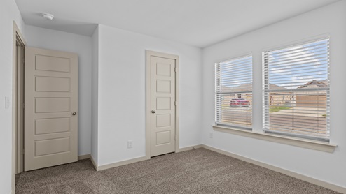 Guest bedroom with plush carpet, spacious closet and two windows