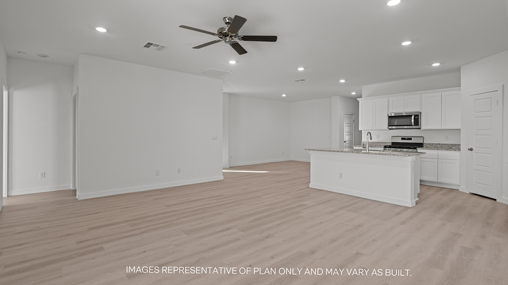Interior living area open to kitchen with center island and white cabinets