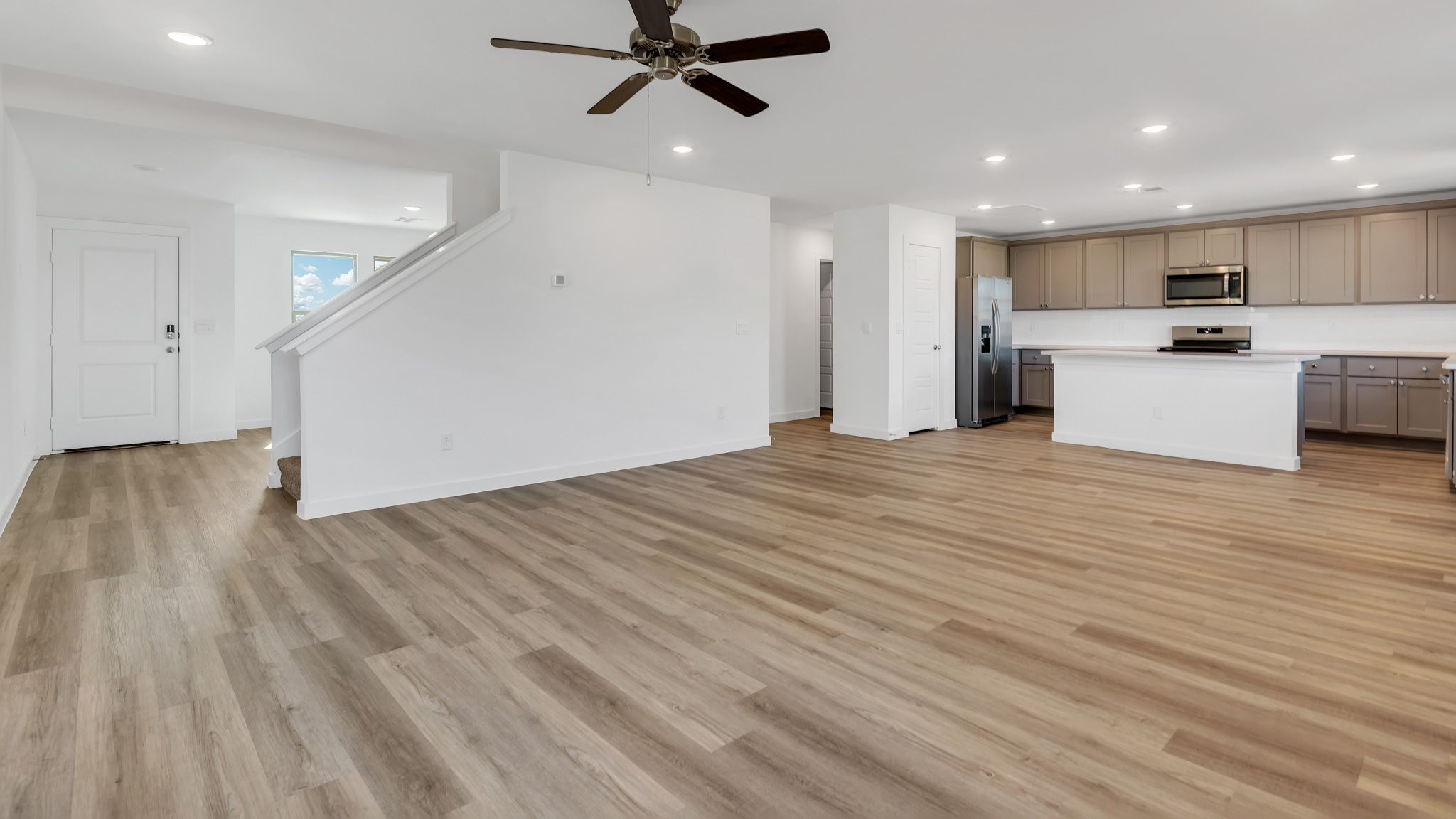 Open concept kitchen, dining, and living area with ample lighting