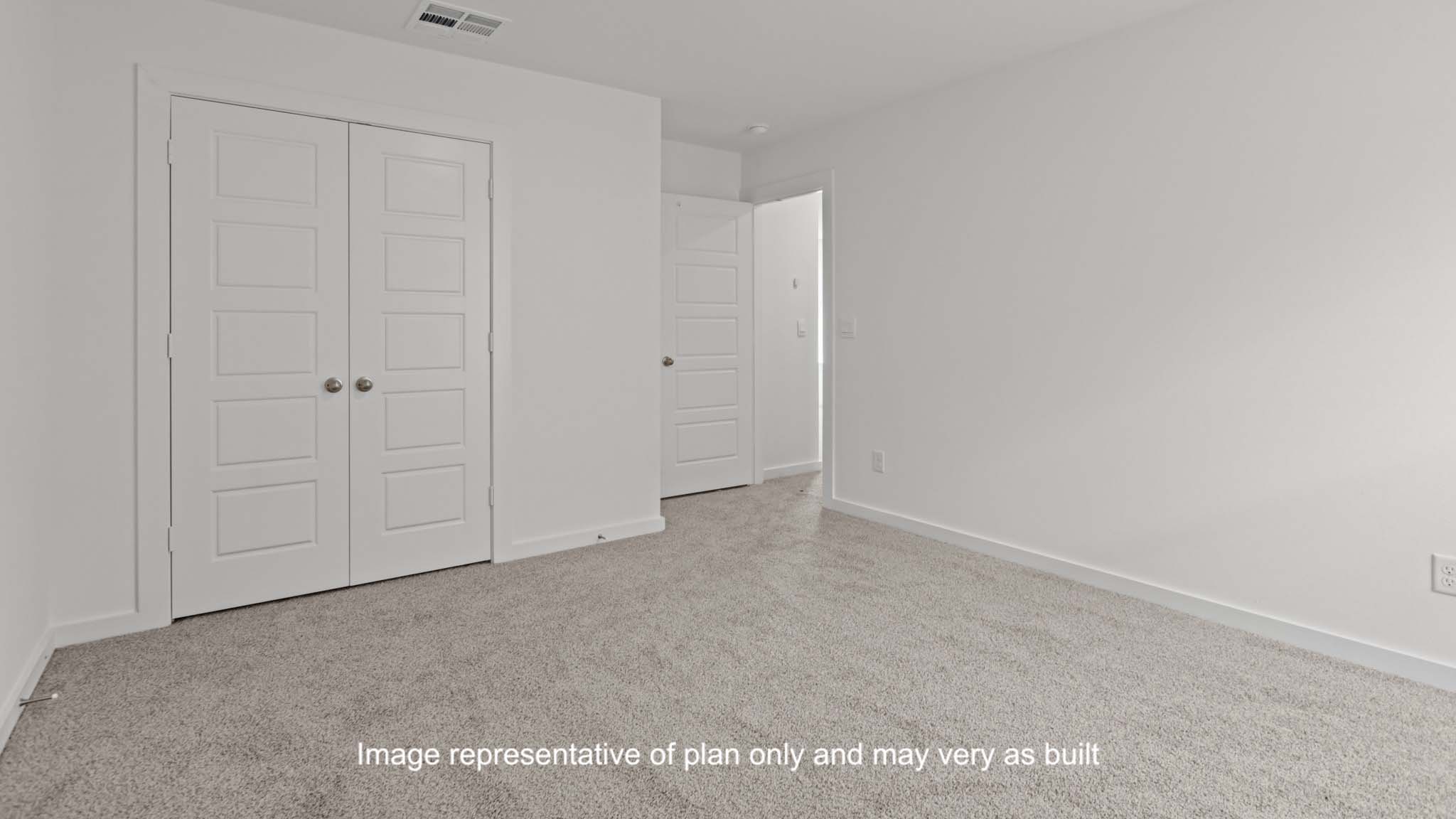 Guest bedroom with plush carpet floors and spacious closet