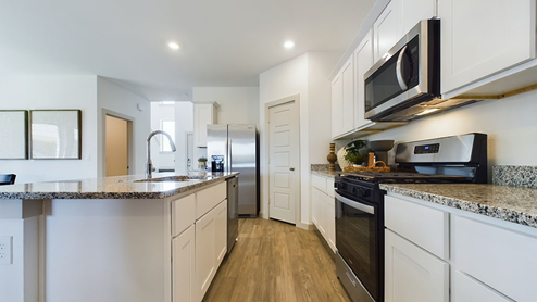Kitchen with spacious island, granite counters, white cabinets and recessed lighting