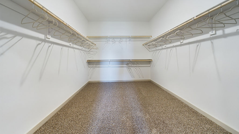 Primary closet with plush carpet and wooden shelving
