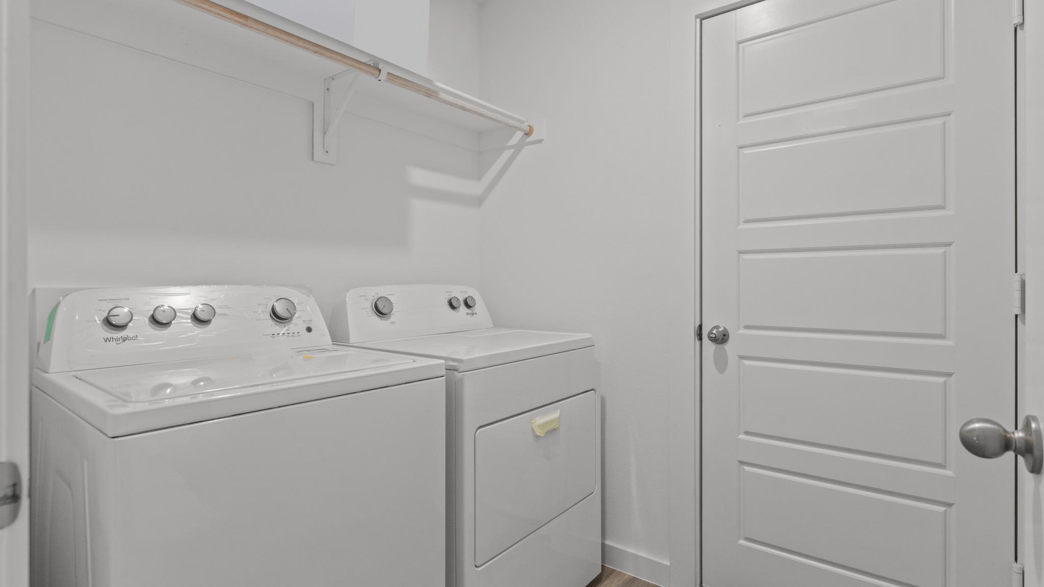 Laundry and utility room with wooden shelving just off the entry way