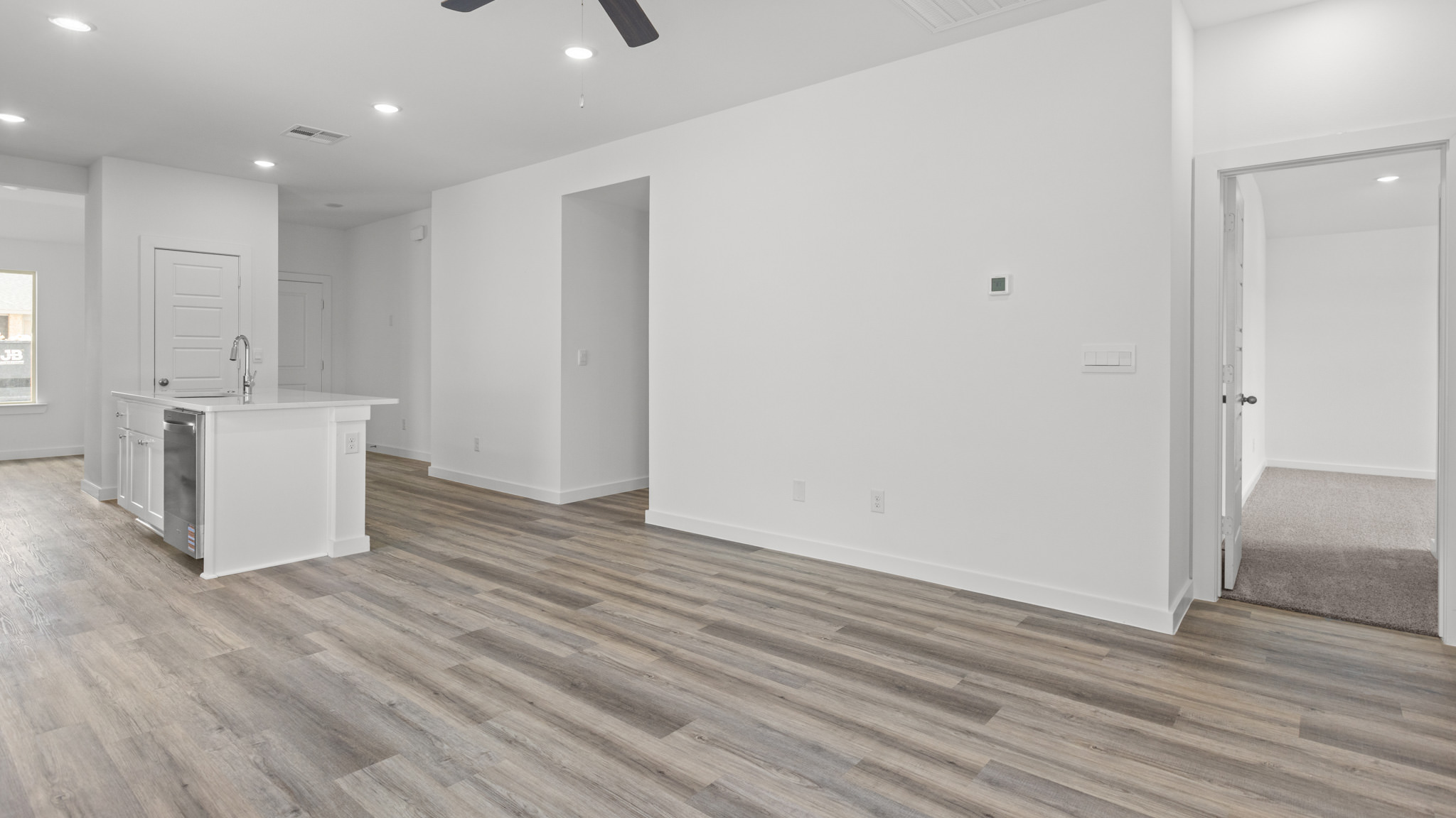 Open airy living room with vinyl plank flooring and windows overlooking the backyard