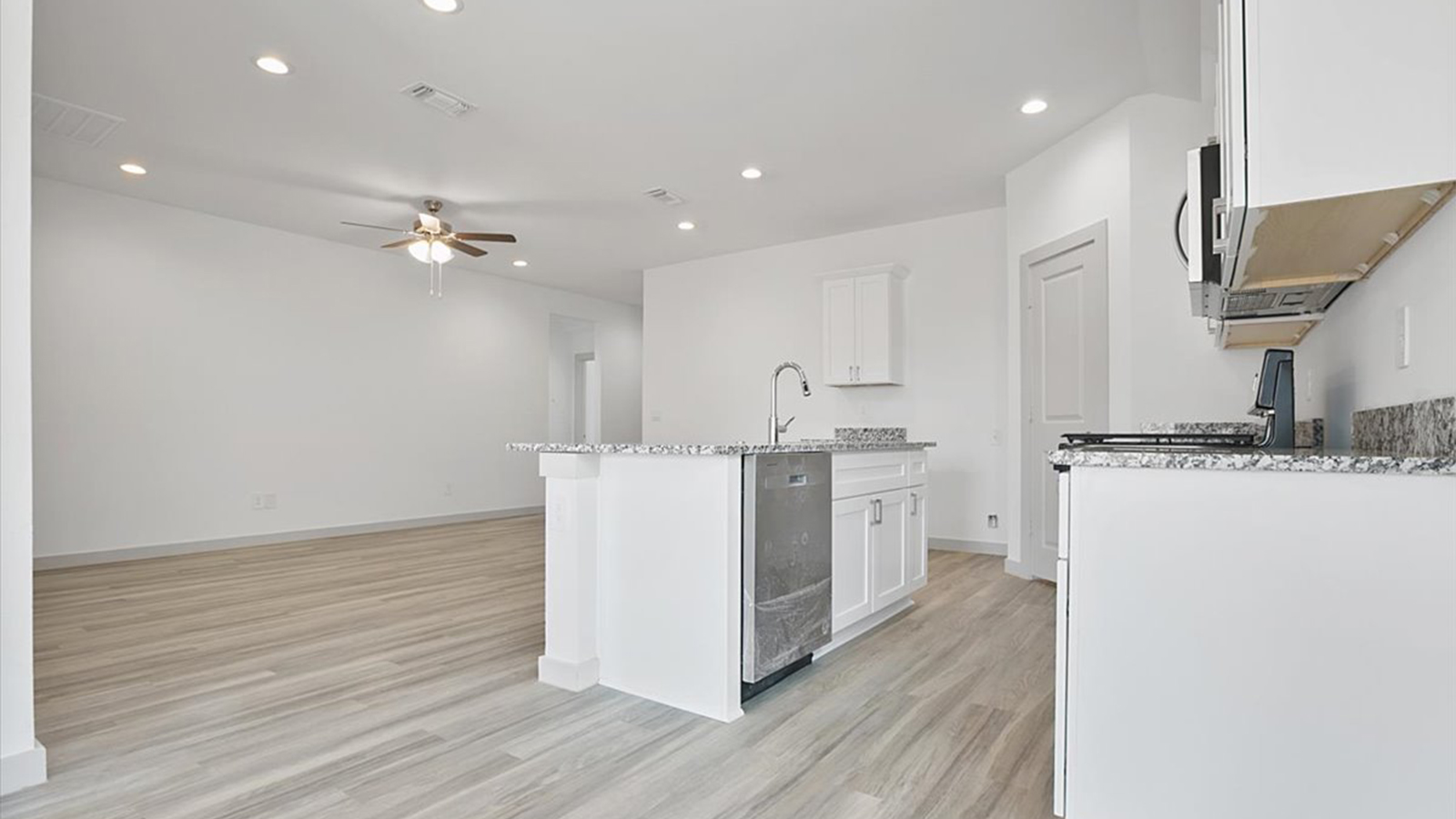 Open concept kitchen with stainless steel appliances, shaker style cabinets, and elevated finishes