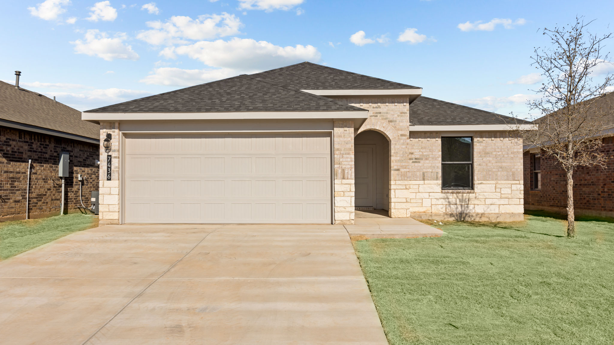 Single- story home with brick, stone, covered patio and two car garage