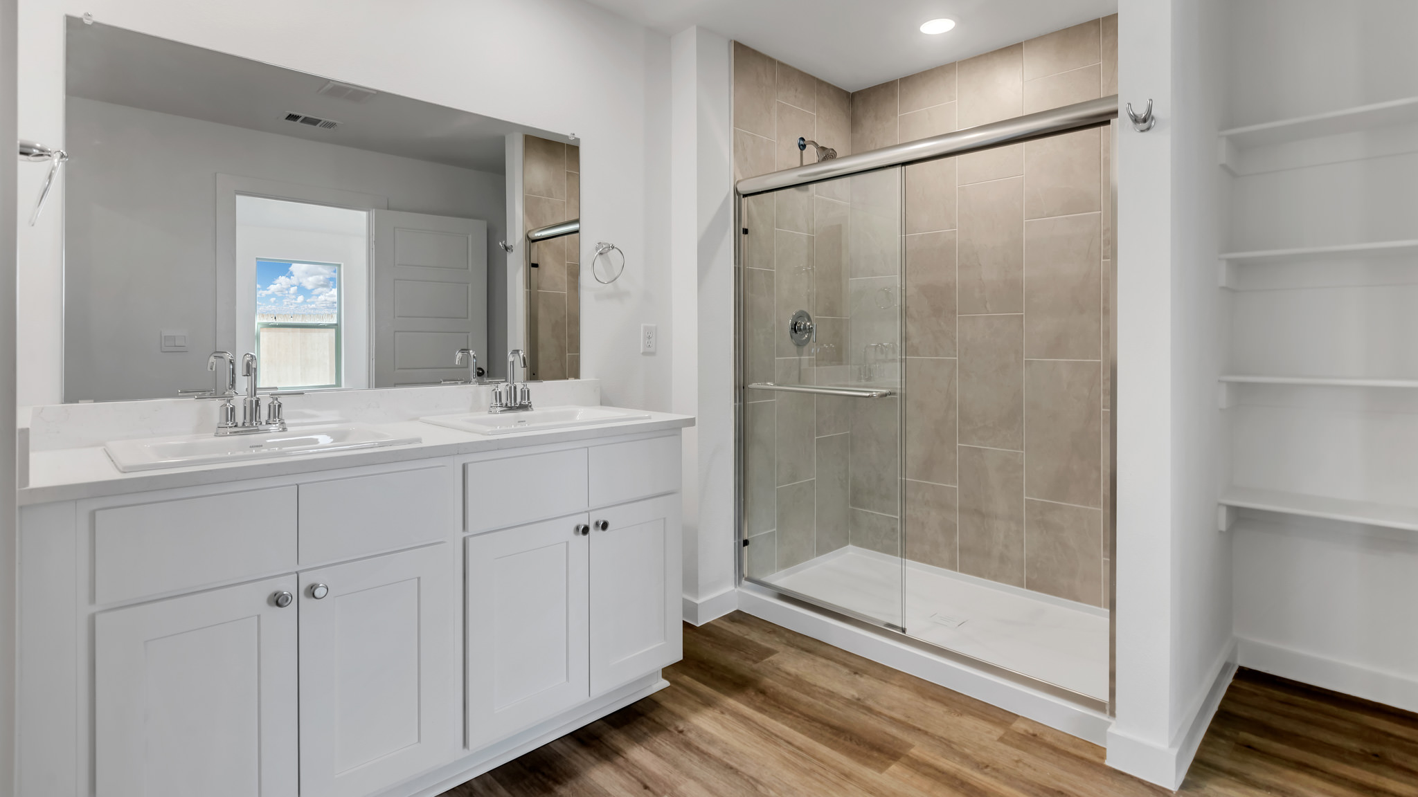 Primary bathroom with built in double sink vanity and luxurious tiled shower