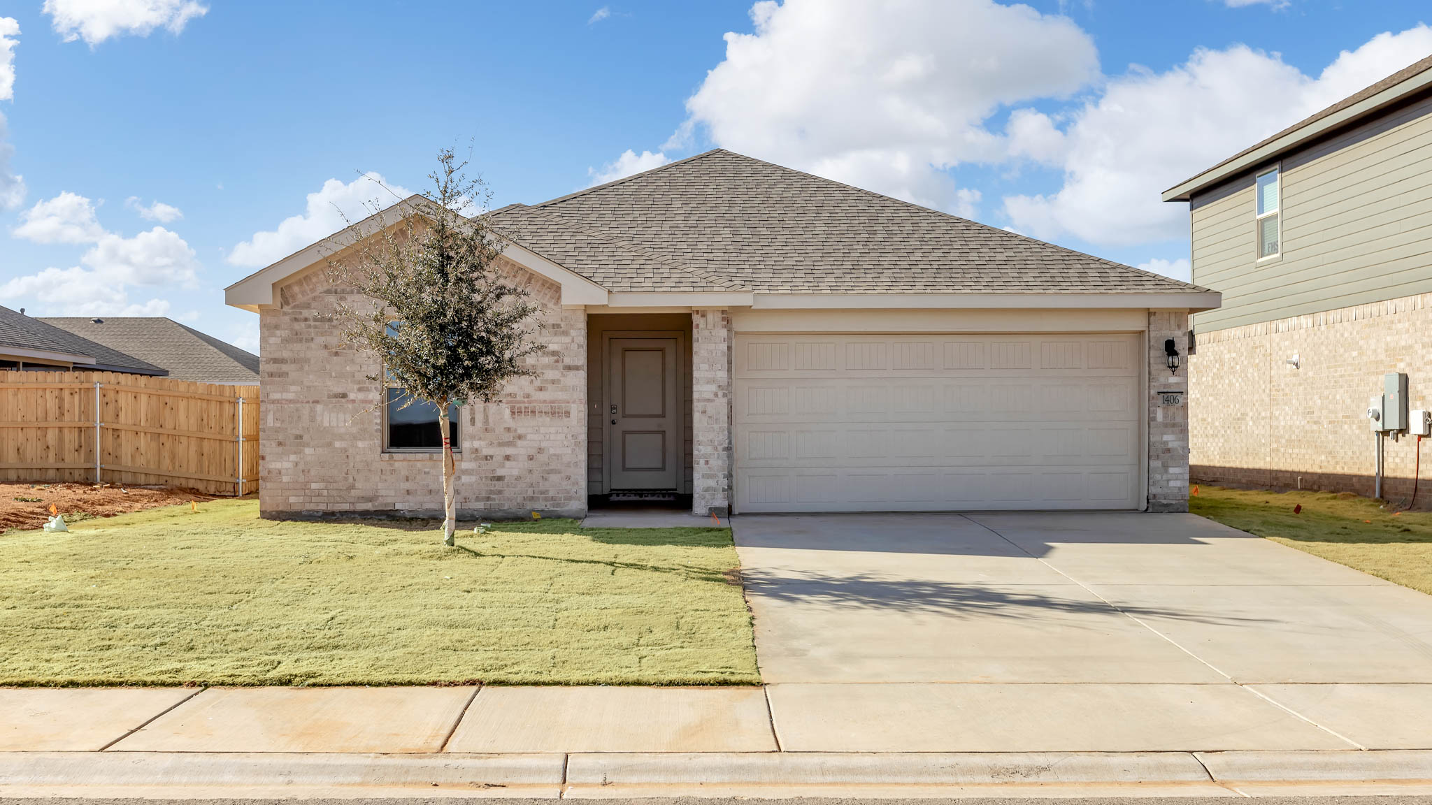 Side view of single- story home with brick, stone, covered patio and two car garage