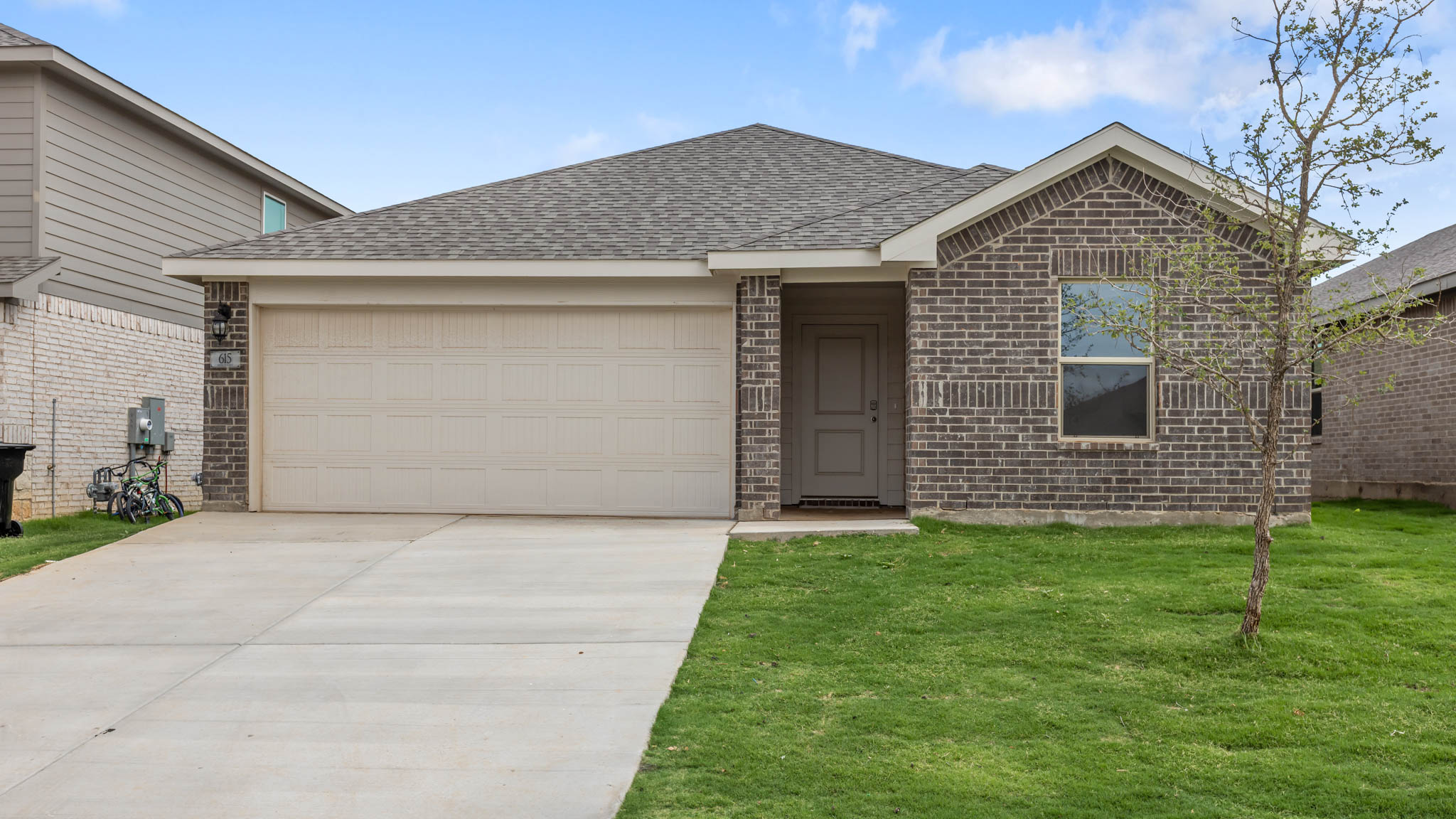 Single story home with brick, covered patio and two car garage