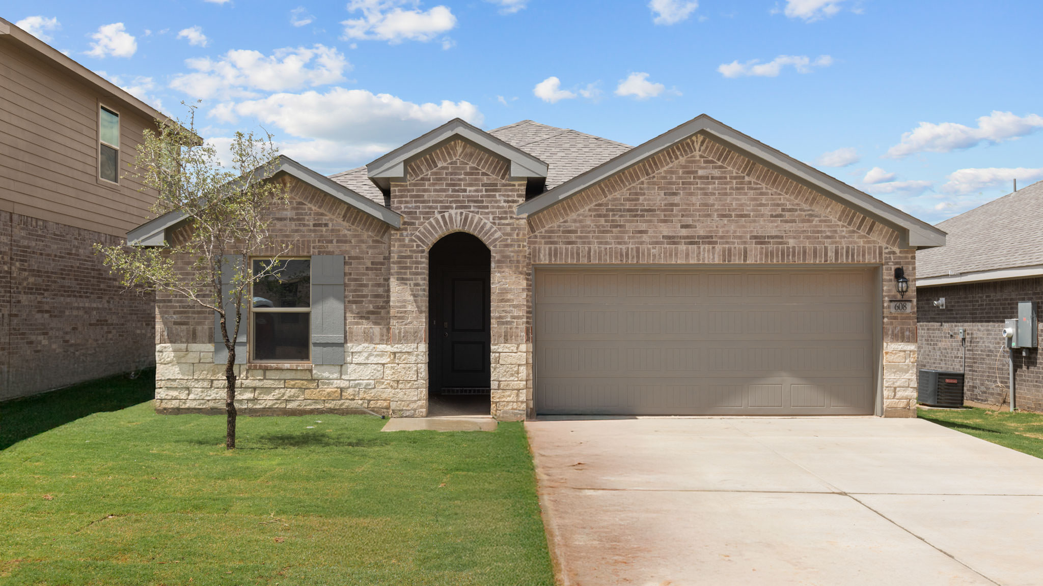 Single- story home with brick, stone, covered patio and two car garage