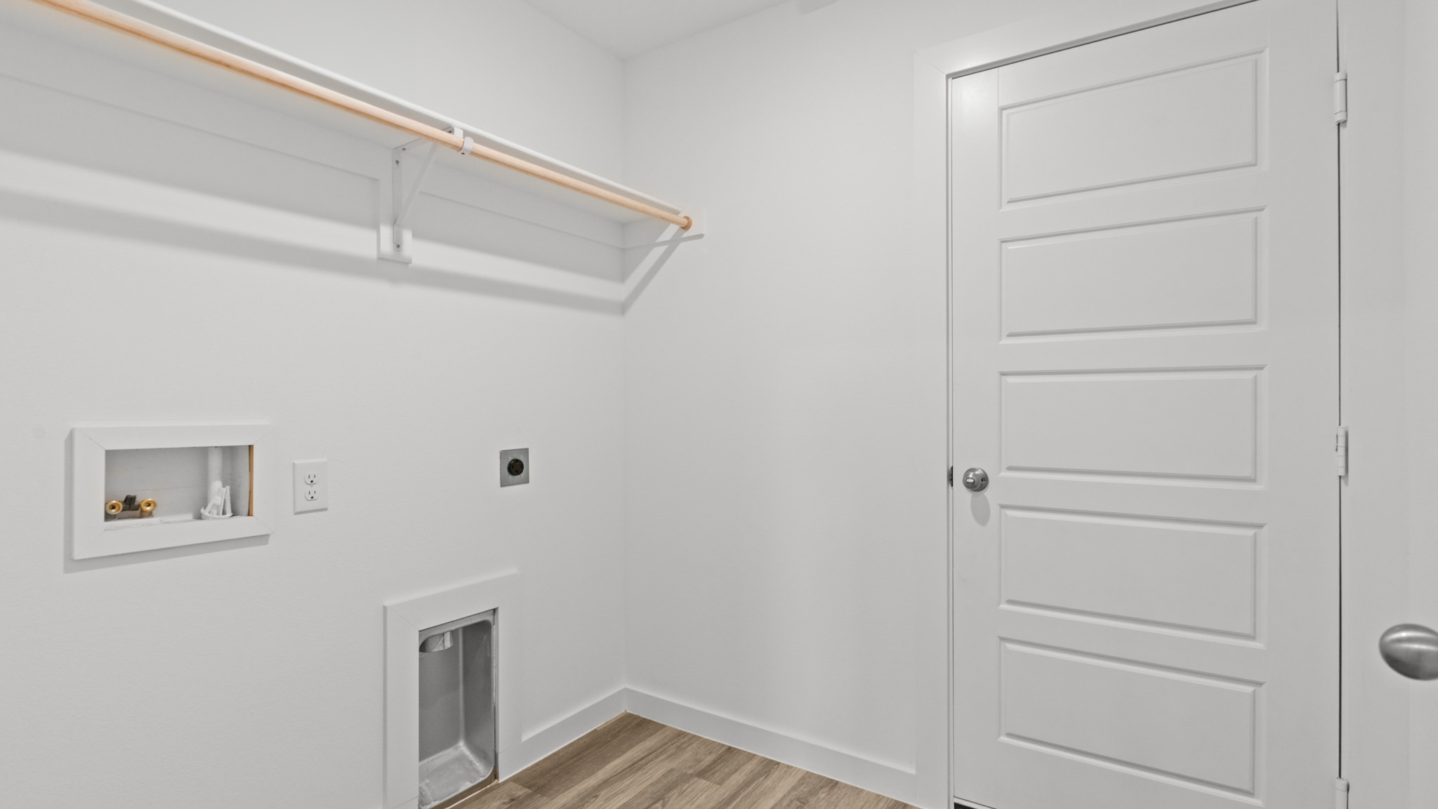 Laundry and utility room with wooden shelving just off the entry way