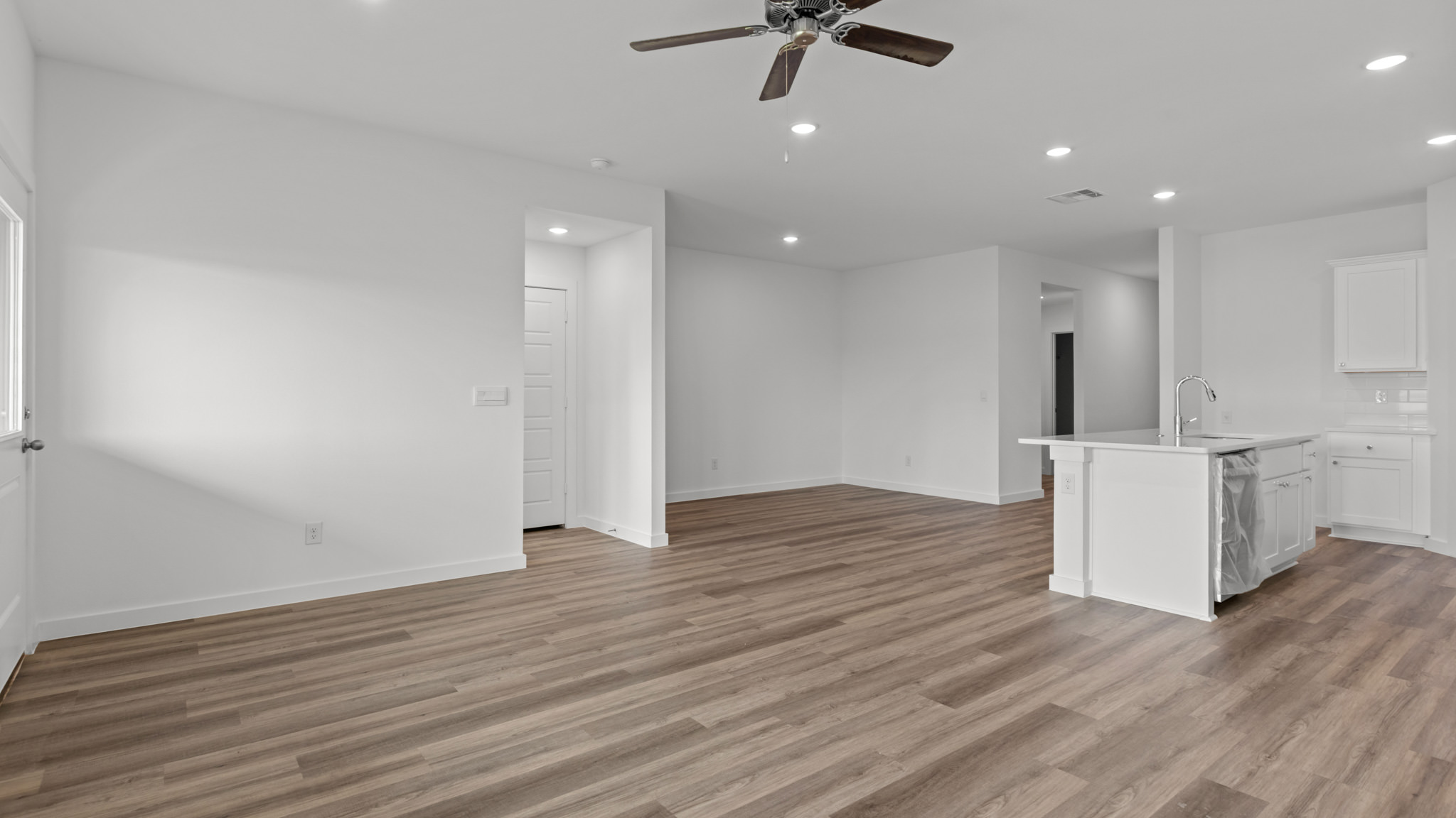 Open airy living room with vinyl plank flooring and windows overlooking the backyard