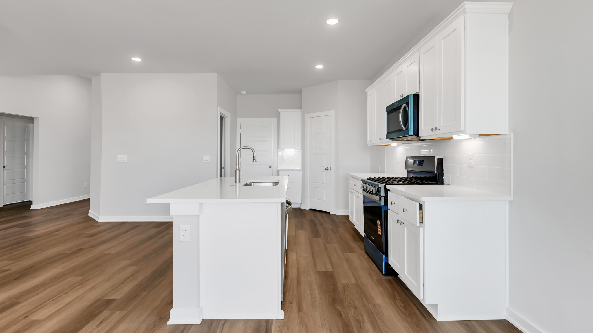 Open concept kitchen with stainless steel appliances, shaker style cabinets, and elevated finishes