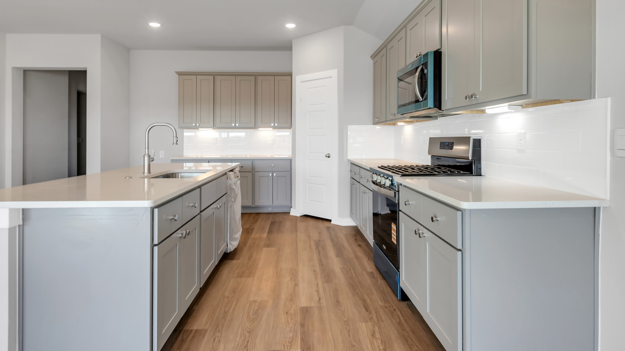 Open concept kitchen with stainless steel appliances, shaker style cabinets, and elevated finishes