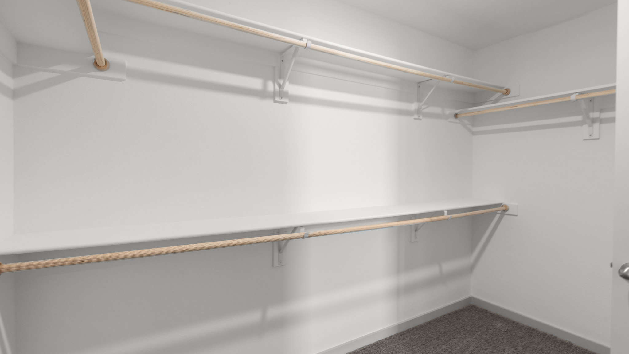 Primary bedroom walk in closet with wooden shelving