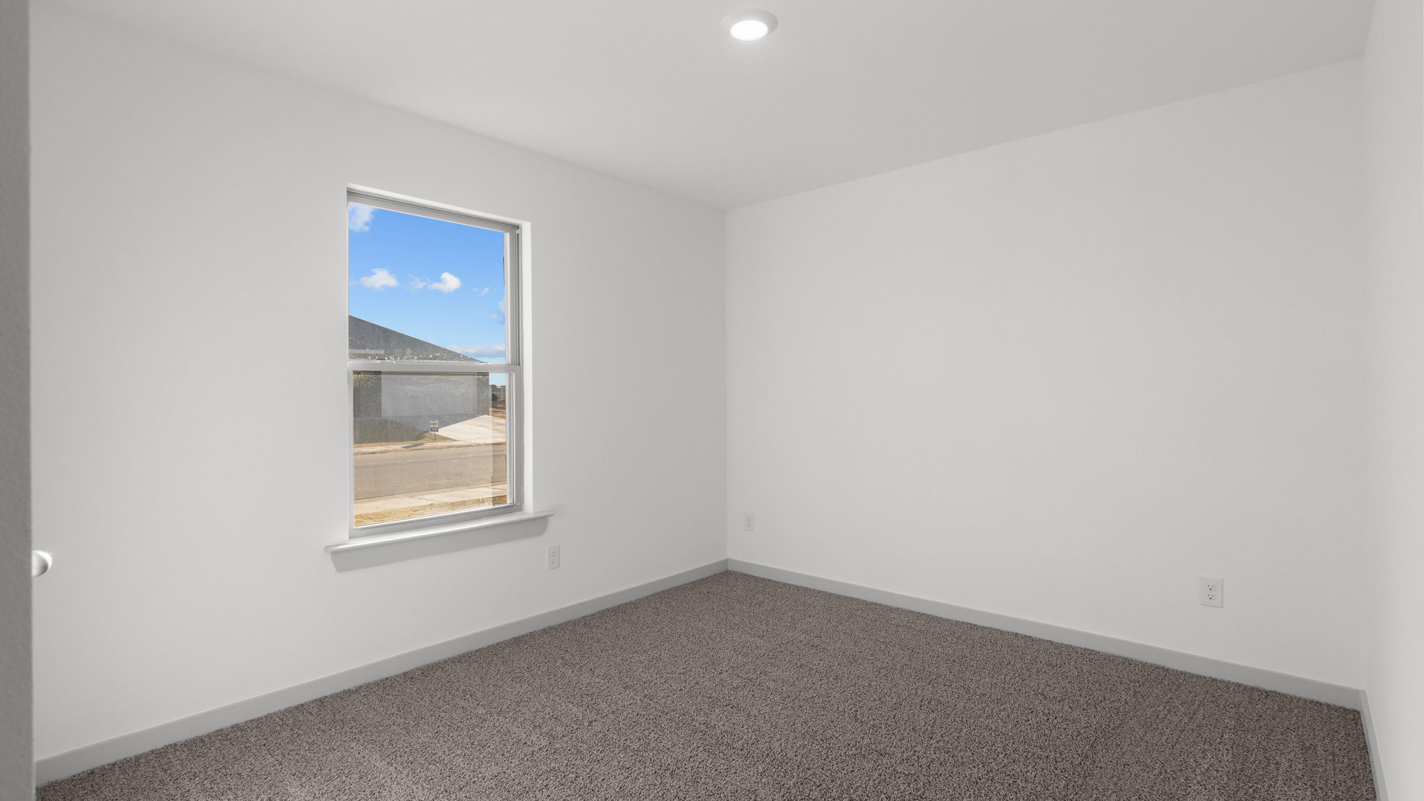 Guest bedroom with plush carpet, window and white interior