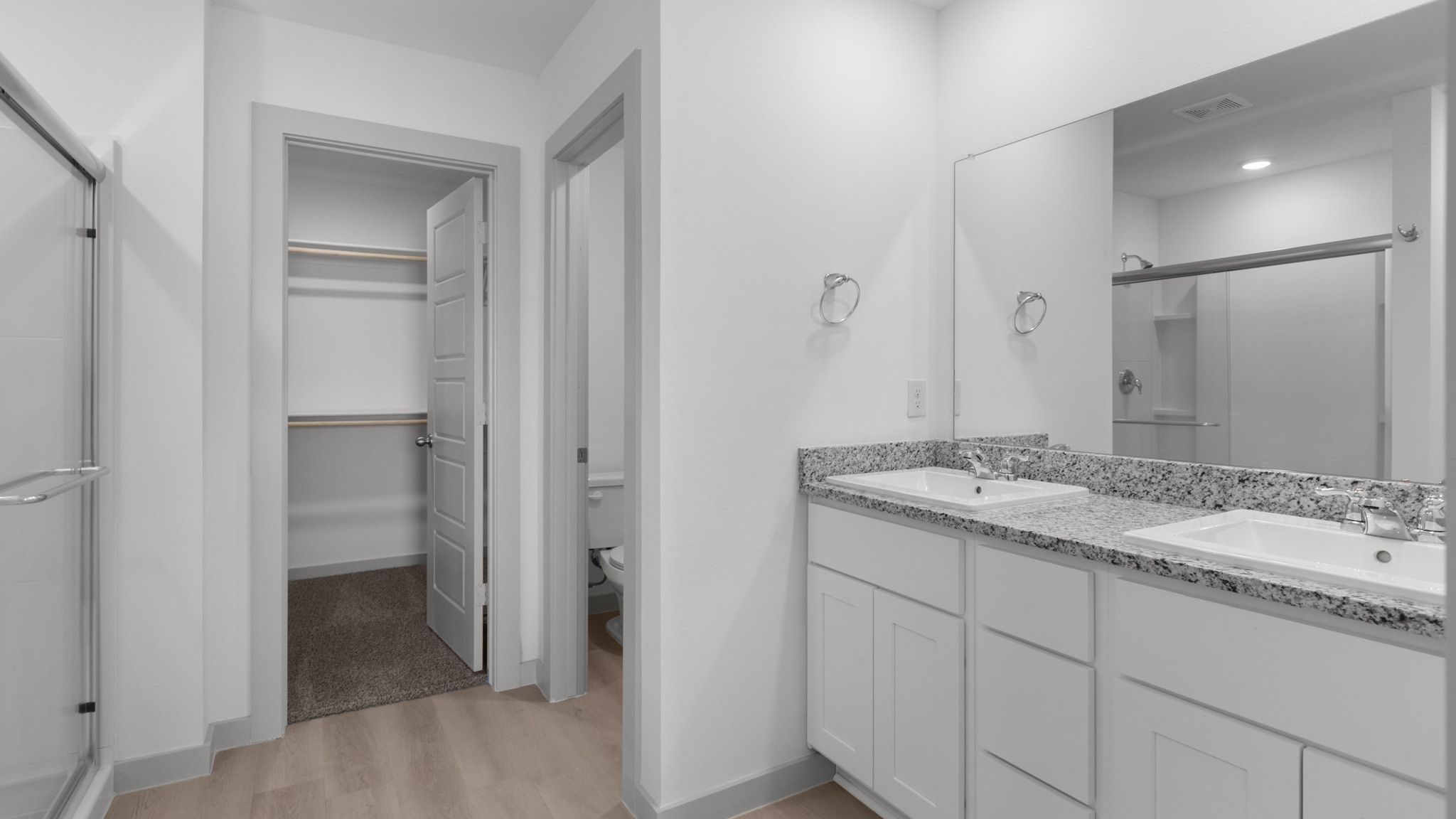 Primary bathroom with dual sink, vanity, granite counters and attached closet