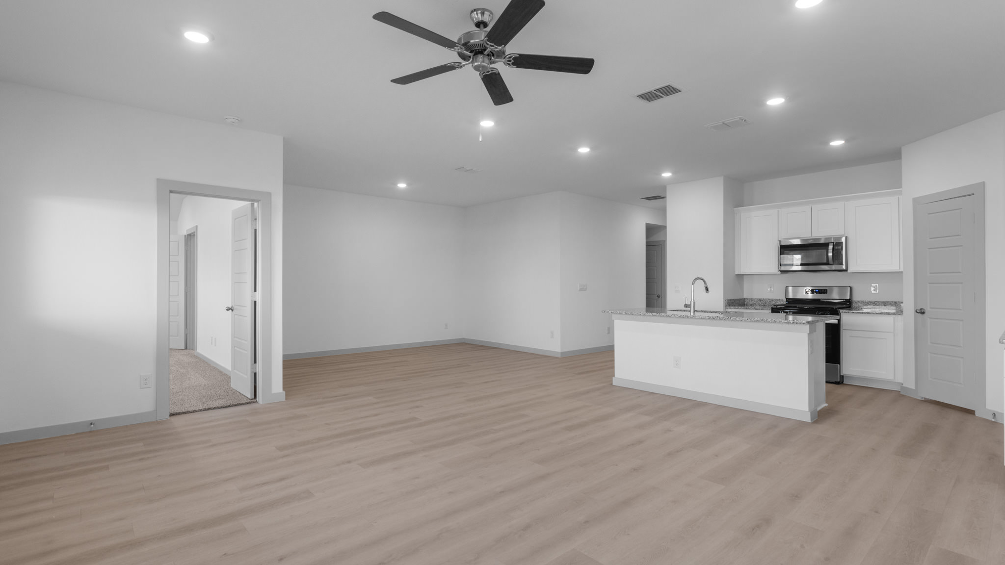 Open airy family room with vinyl plank flooring and windows overlooking backyard