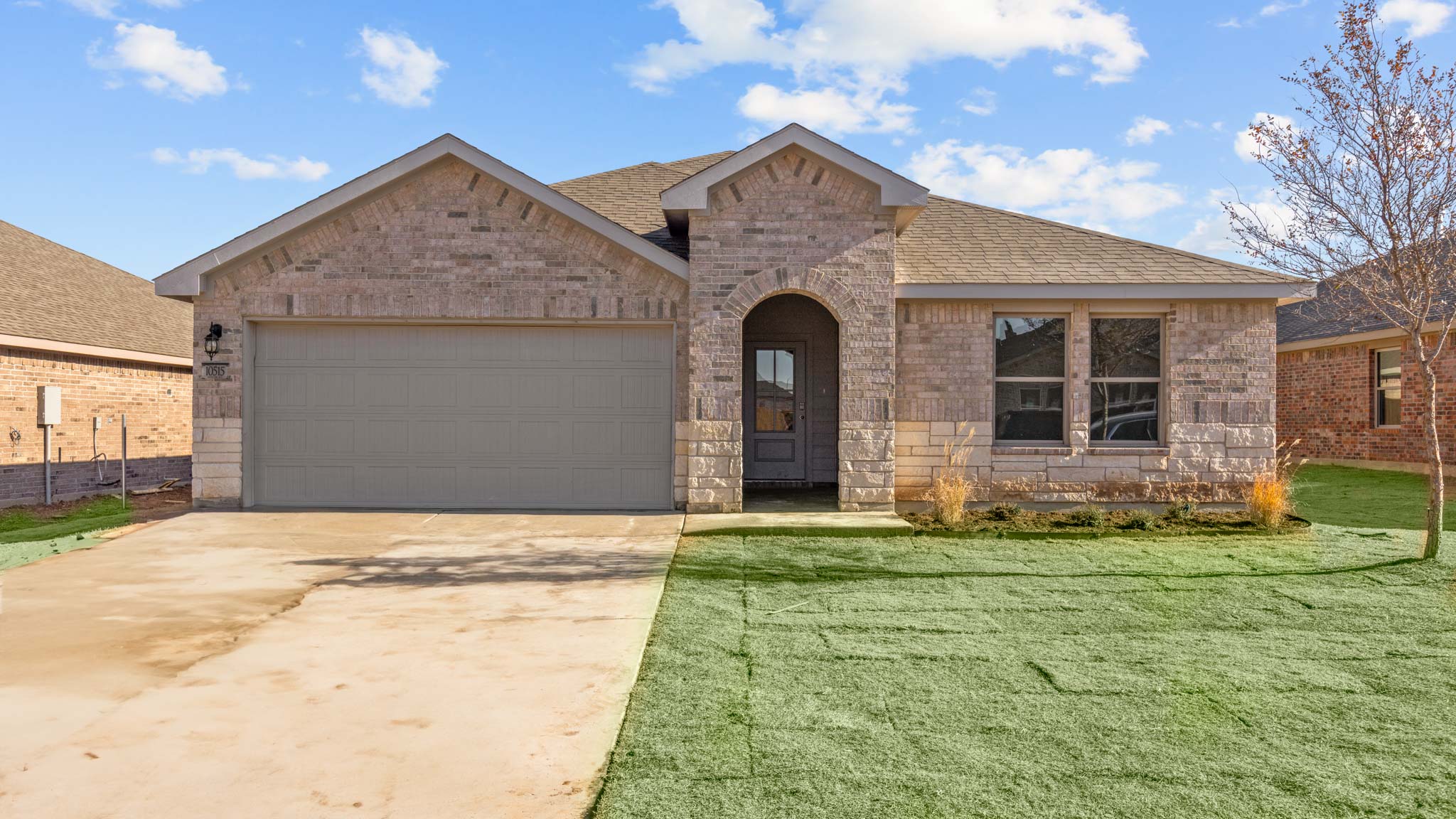 Single- story home with brick, stone, covered patio and two car garage