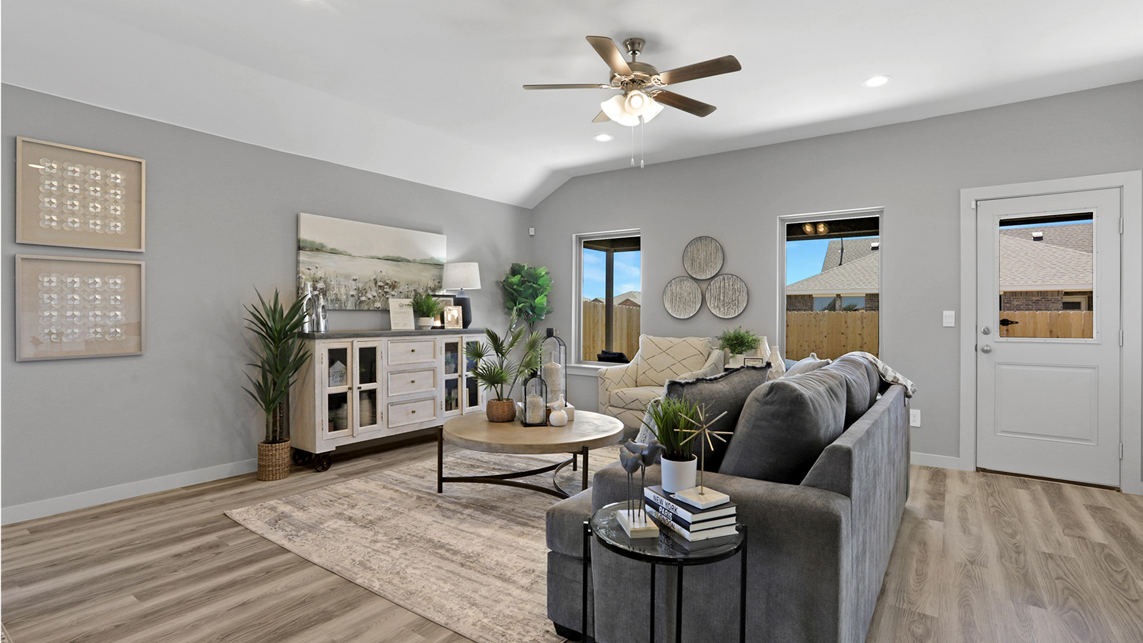 Open airy living area with vinyl plank flooring recessed lights and windows overlooking backyard