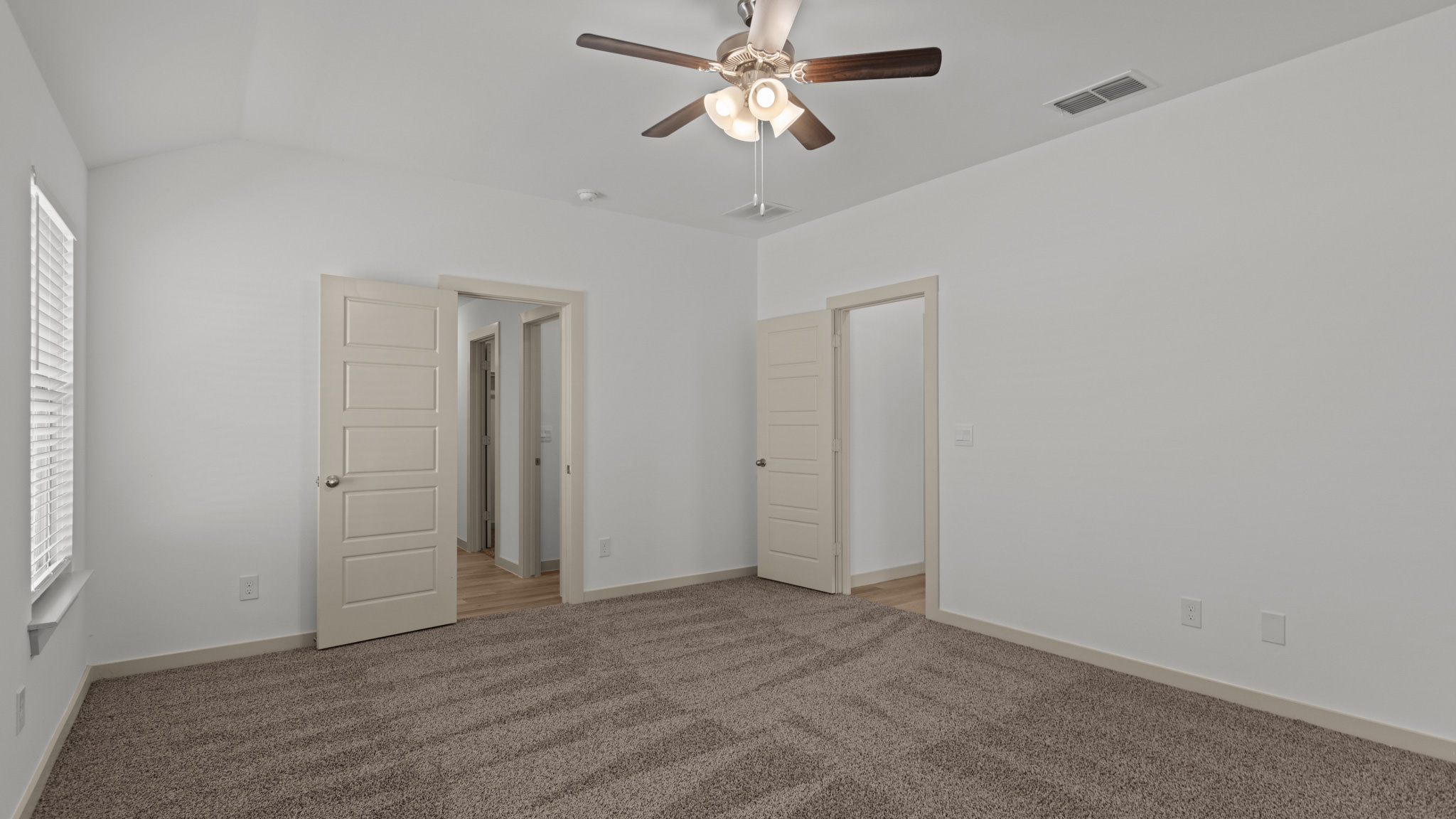 Primary bedroom with plush carpet, ceiling fan and white interior