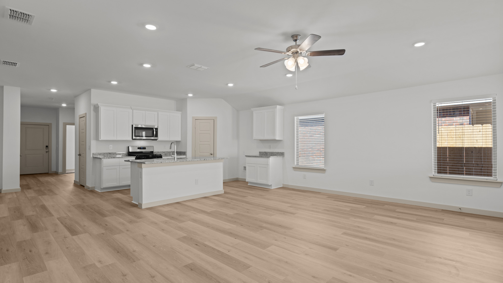 Open concept kitchen and living area with vinyl plank flooring and recessed lighting