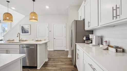 white kitchen with white island and stainless-steel appliances and silver finishes