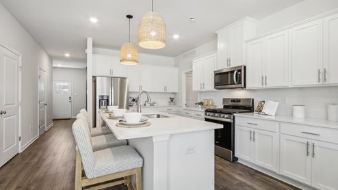 white kitchen with white island and stainless-steel appliances and silver finishes