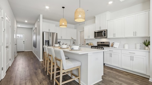 white kitchen with white island and stainless-steel appliances and silver finishes