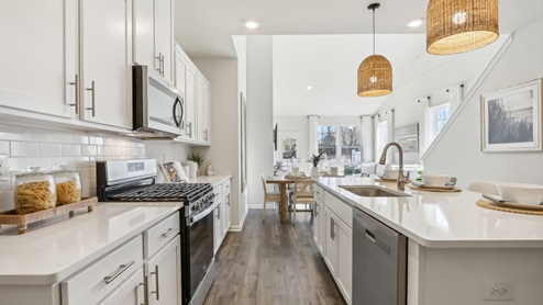white kitchen with white island and stainless-steel appliances and silver finishes
