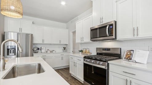 white kitchen with white island and stainless-steel appliances and silver finishes