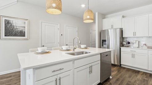 white kitchen with white island and stainless-steel appliances and silver finishes