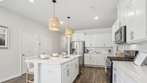 white kitchen with white island and stainless-steel appliances and silver finishes