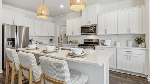 white kitchen with white island and stainless-steel appliances and silver finishes