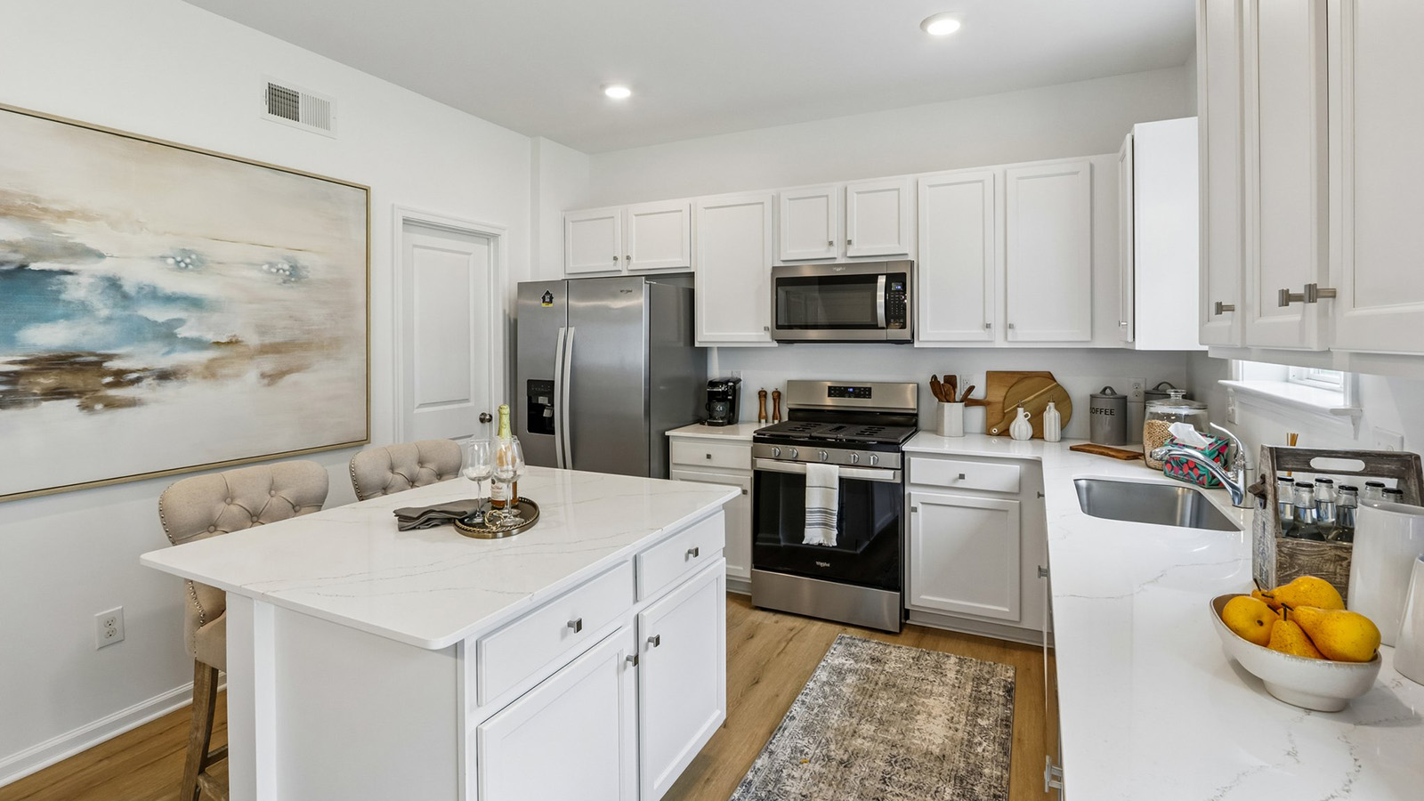 modern kitchen with quartz island, white cabinetry and stainless steel appliances