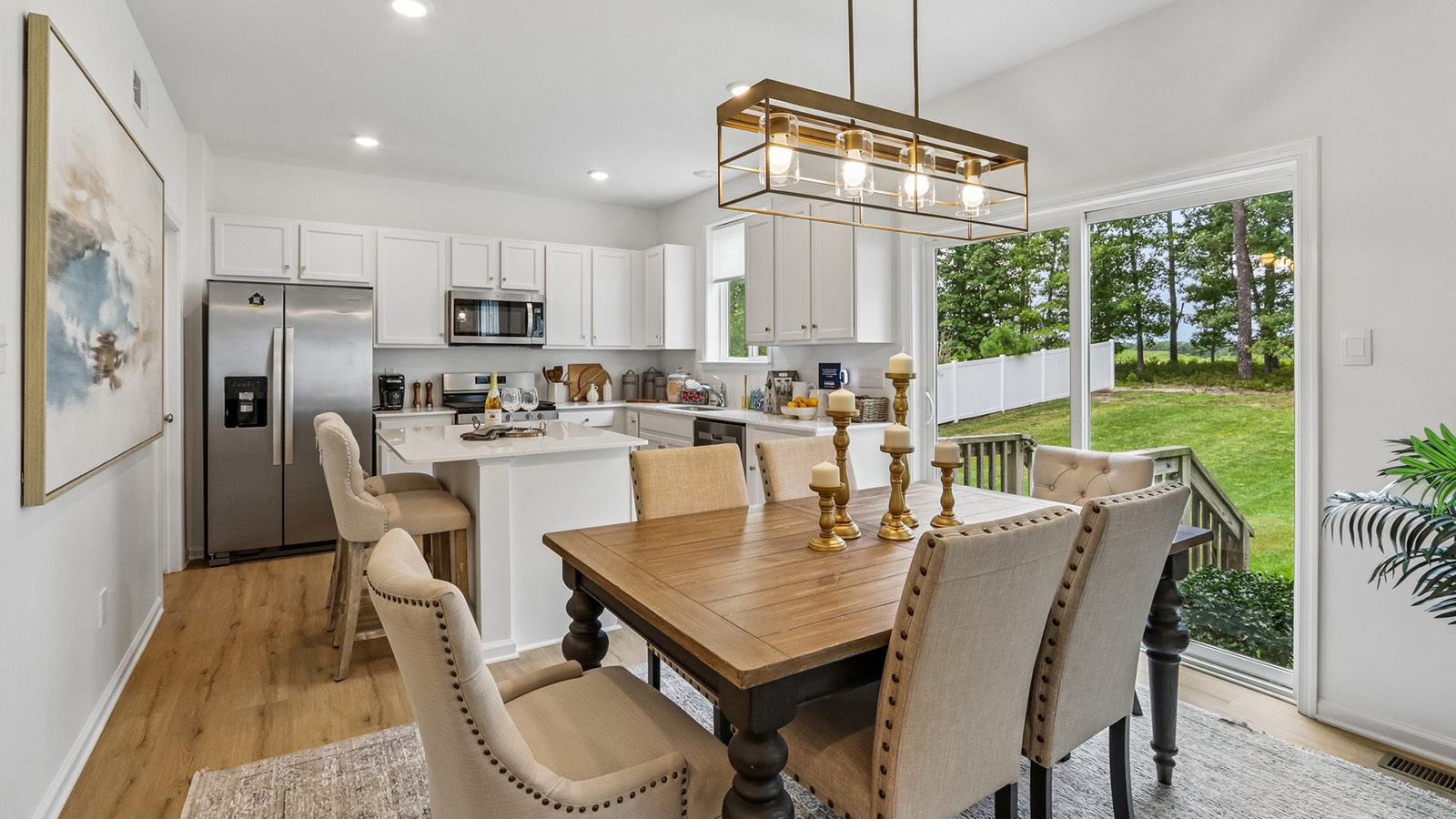 spacious main floor featuring the dining table and spacious kitchen with quartz island, white cabinetry, and stainless steel appliances
