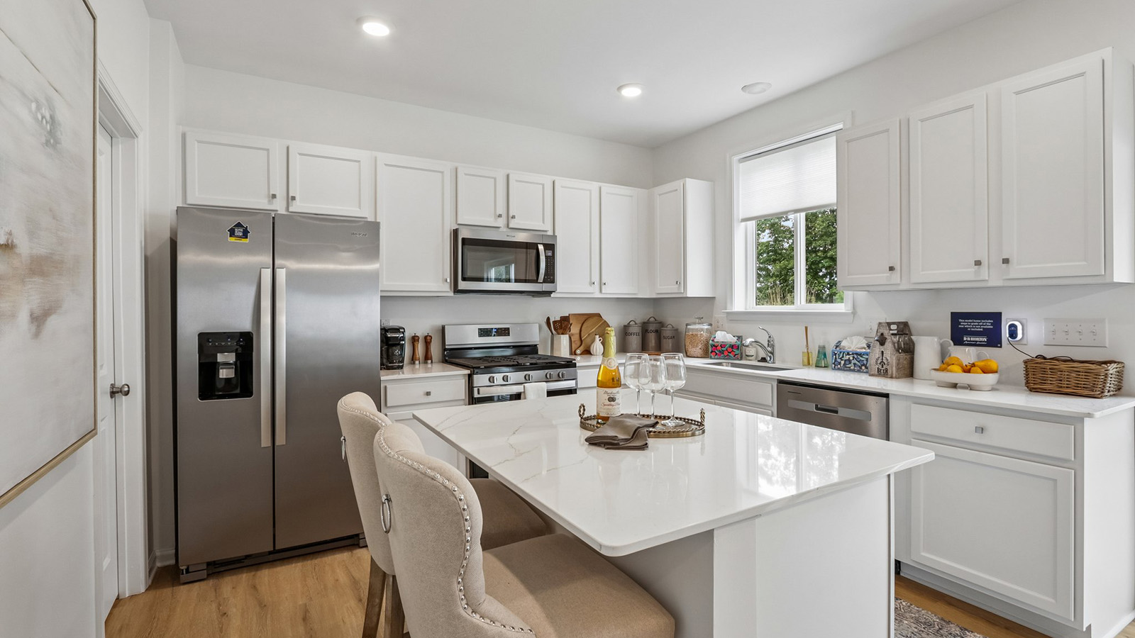 spacious kitchen design with large quartz island, white cabinetry and stainless steel appliances