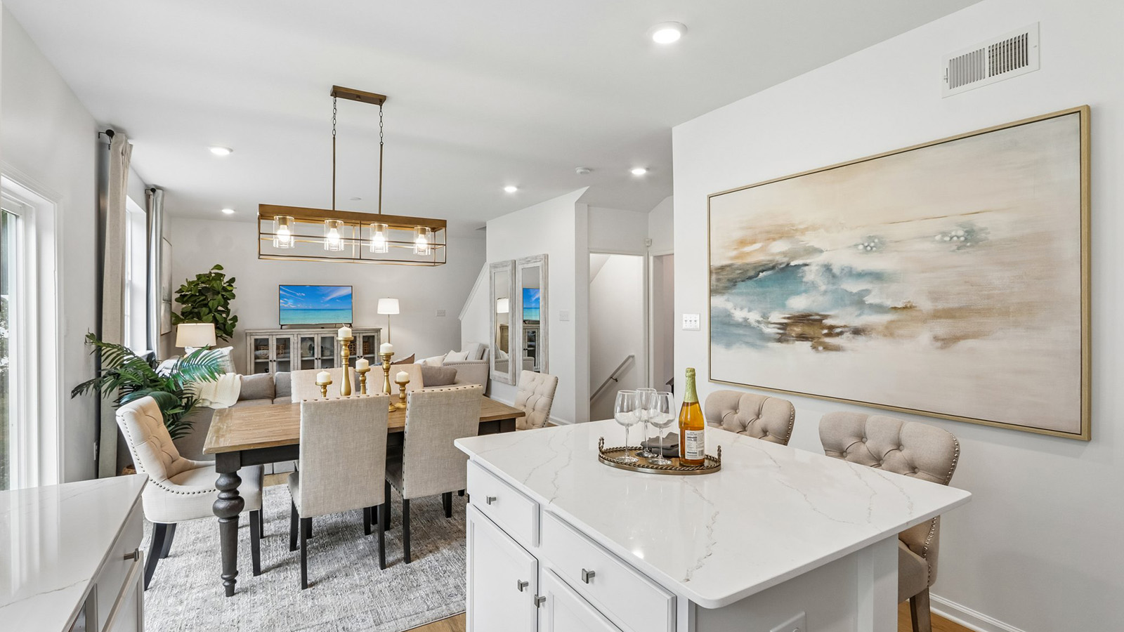 spacious main floor featuring the dining table and spacious kitchen with quartz island, white cabinetry, and stainless steel appliances