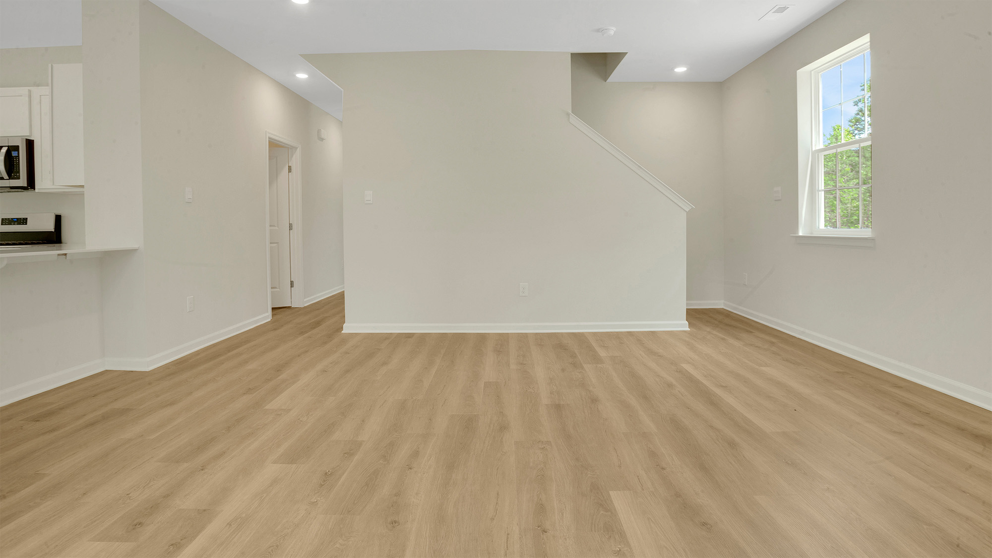 open concept first floor layout, featuring the large kitchen island, living room, and light hardwood floors throughout