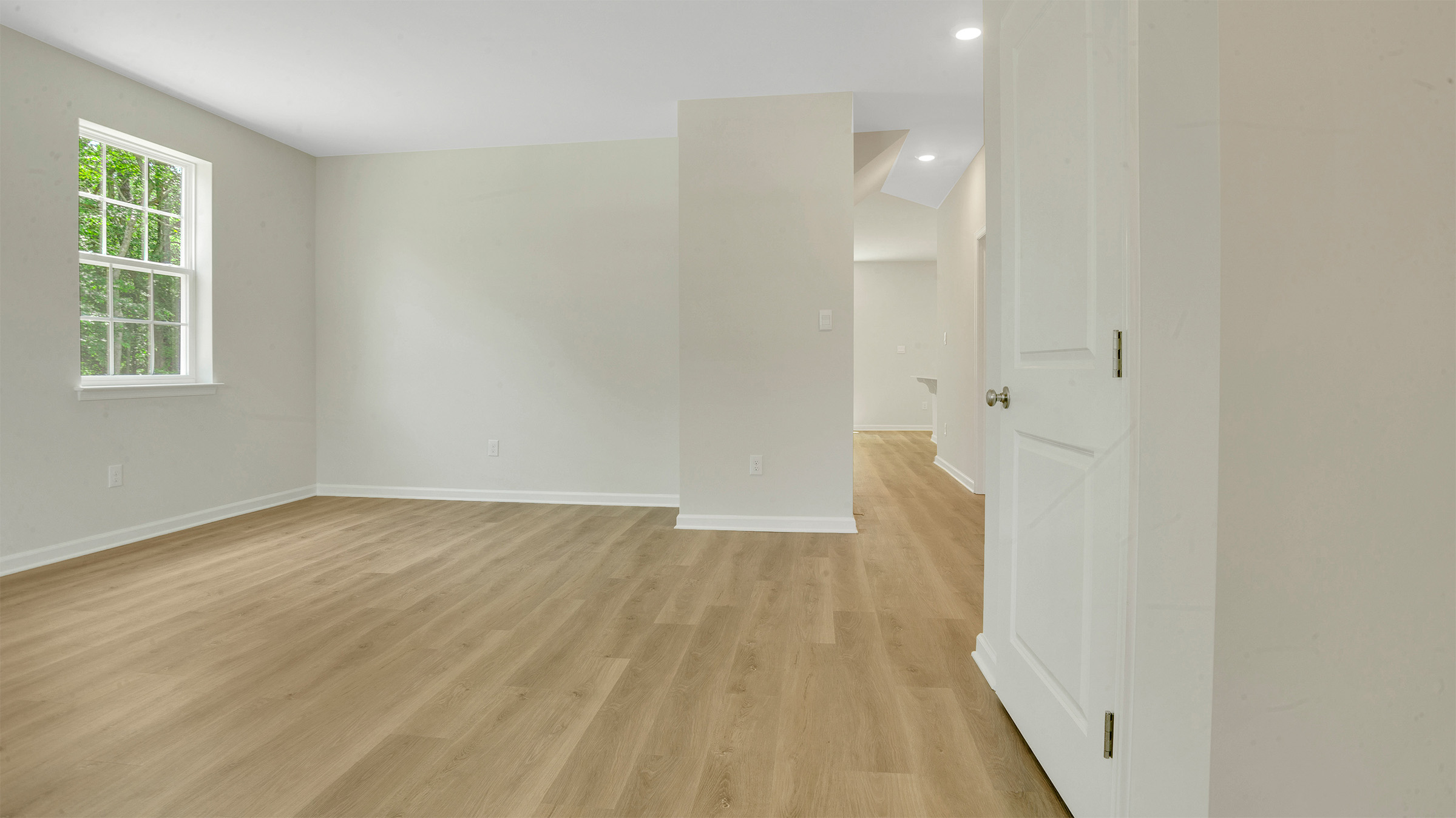 open concept first floor layout, featuring the large kitchen island, living room, and light hardwood floors throughout